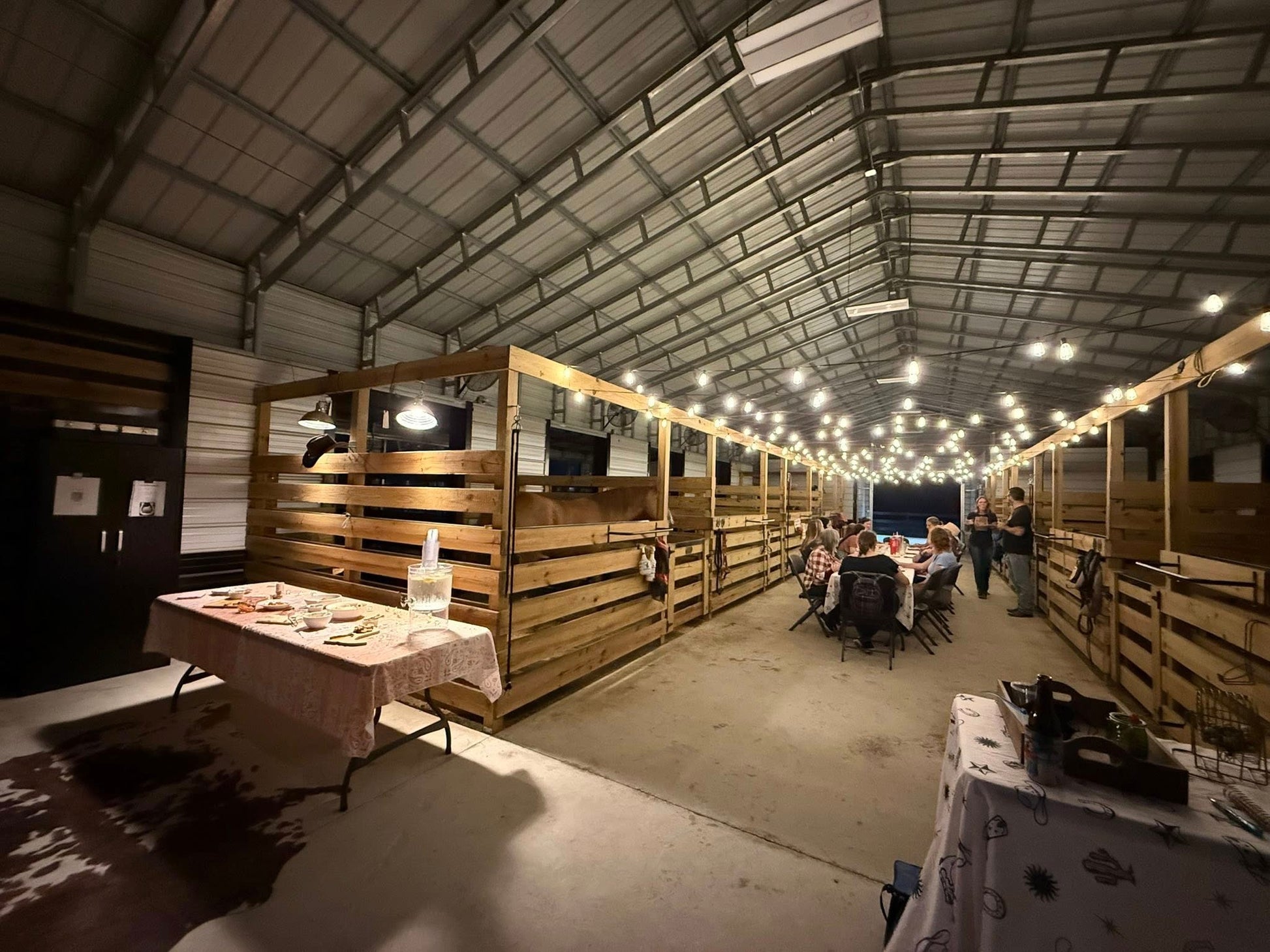 Wide view of the Rodeo Stables barn event space set up for Bingo Night with tables, lights, and guests.