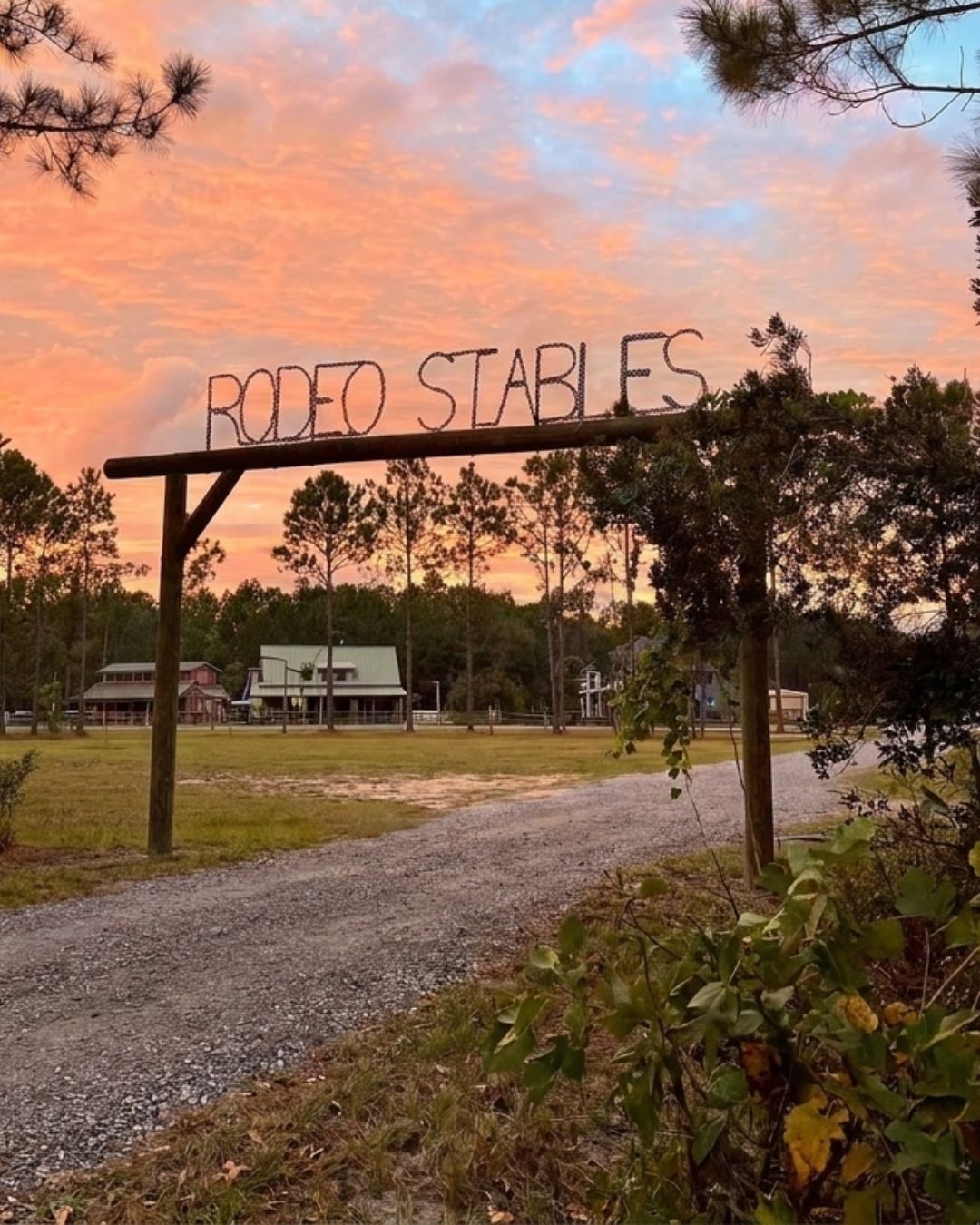 Rodeo Stables entrance sign at sunset with horse farm and fencing