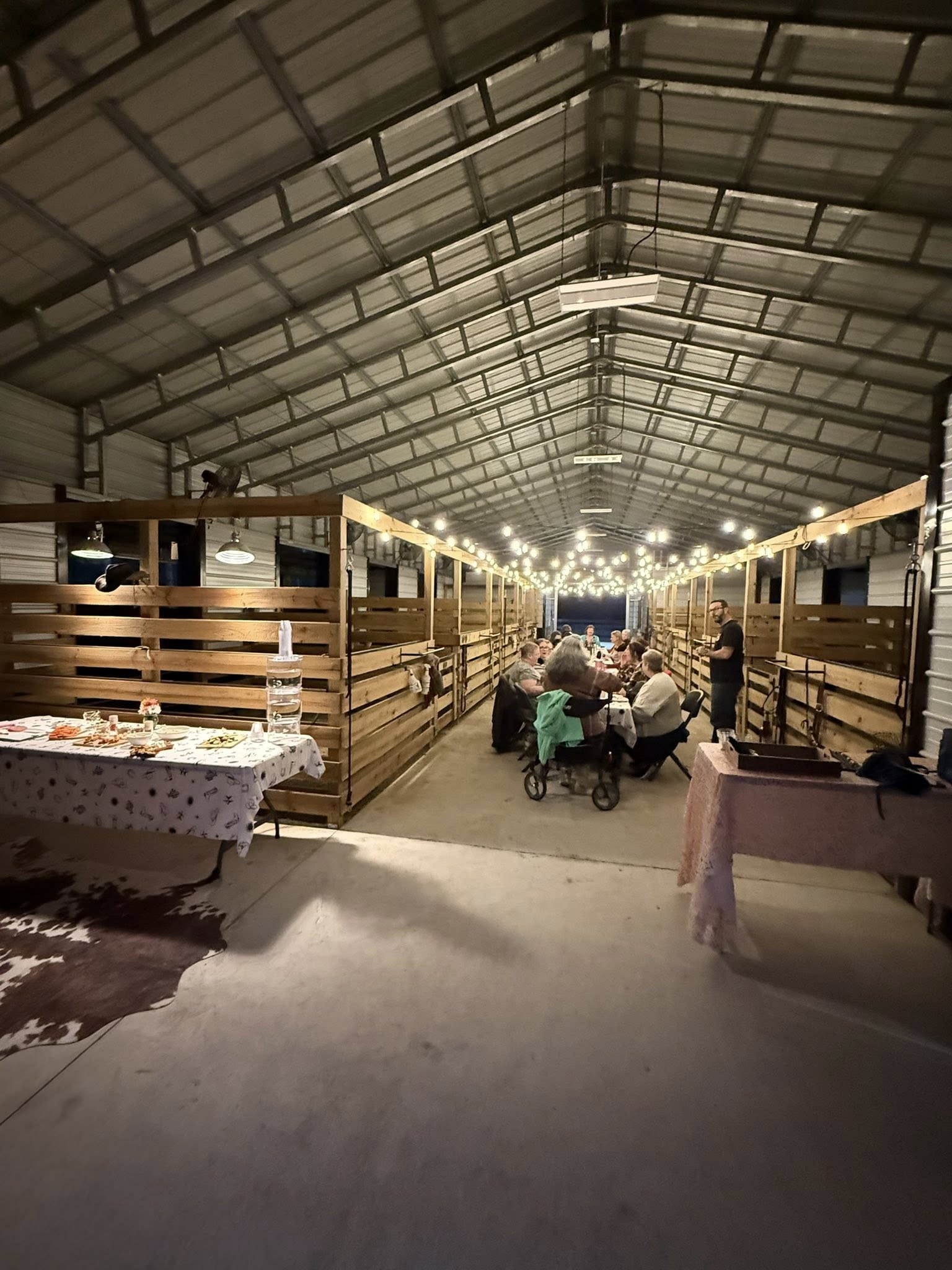 Private gathering inside the Rodeo Stables barn with guests dining under string lights in Ormond Beach, Florida.