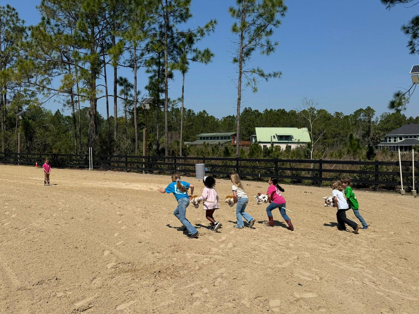 Kids running and playing barn games in the outdoor riding arena at Rodeo Stables.