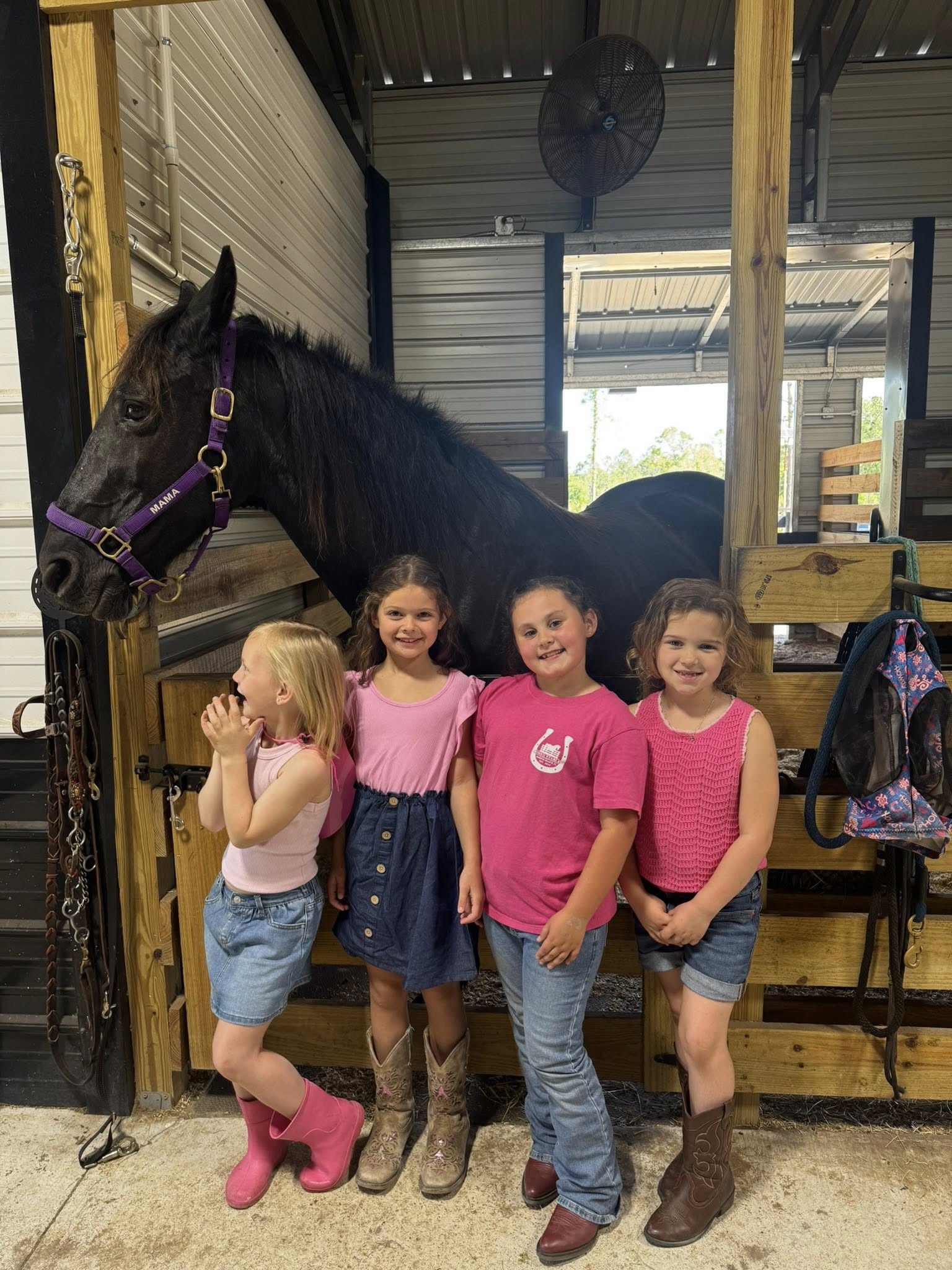 Children posing beside a horse inside the Rodeo Stables barn during a kids horse activity event.
