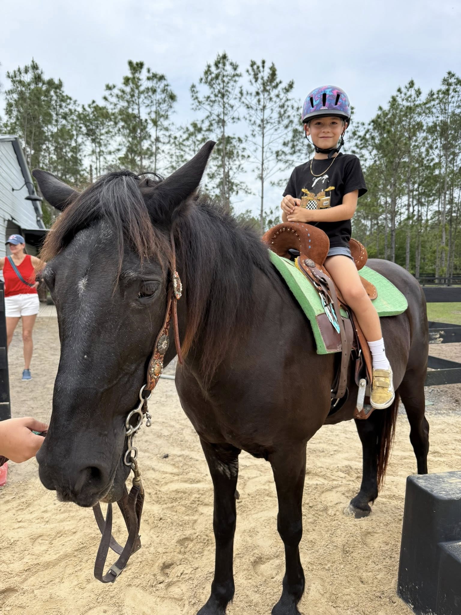 Child riding a horse with a helmet on  at Rodeo Stables.
