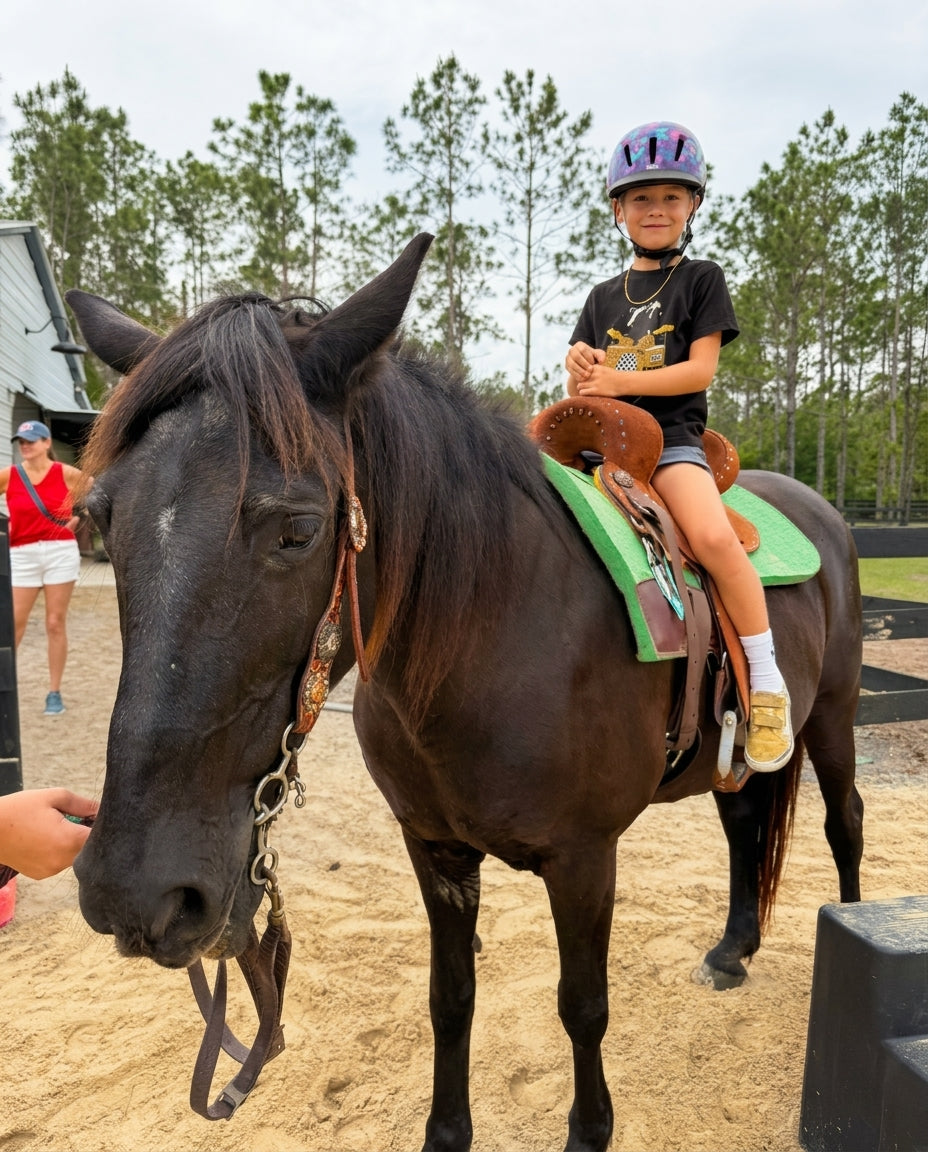 Child wearing a riding helmet during a horseback riding activity at Rodeo Stables.