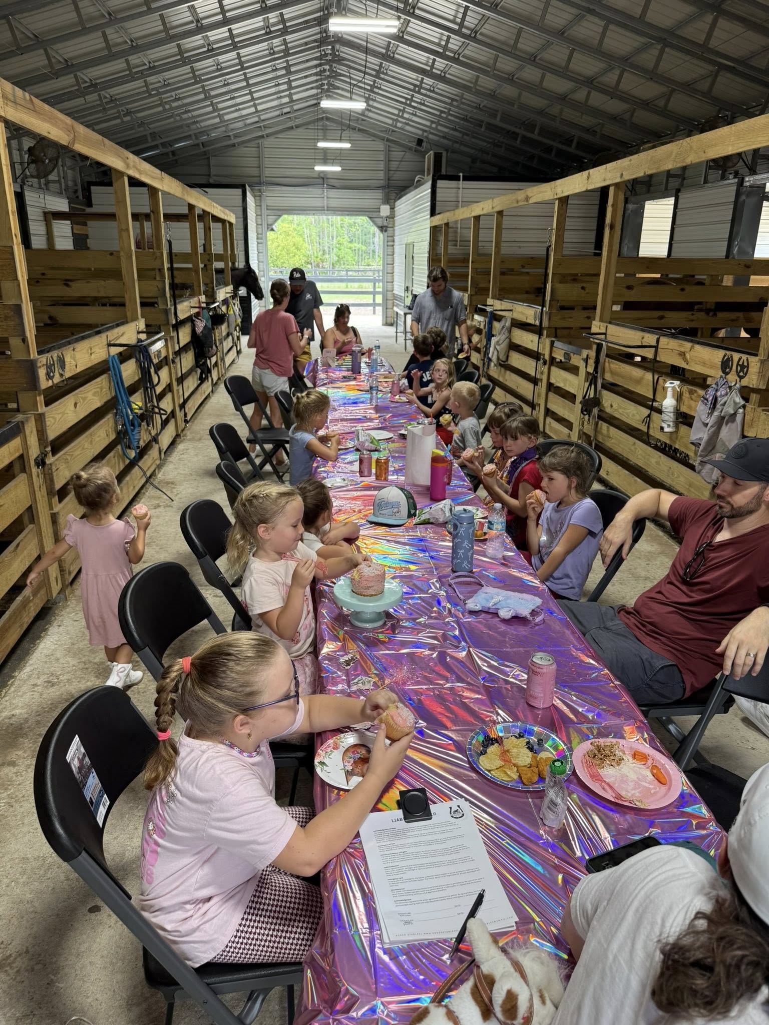 Kids seated at a decorated party table during a birthday celebration inside the Rodeo Stables barn.