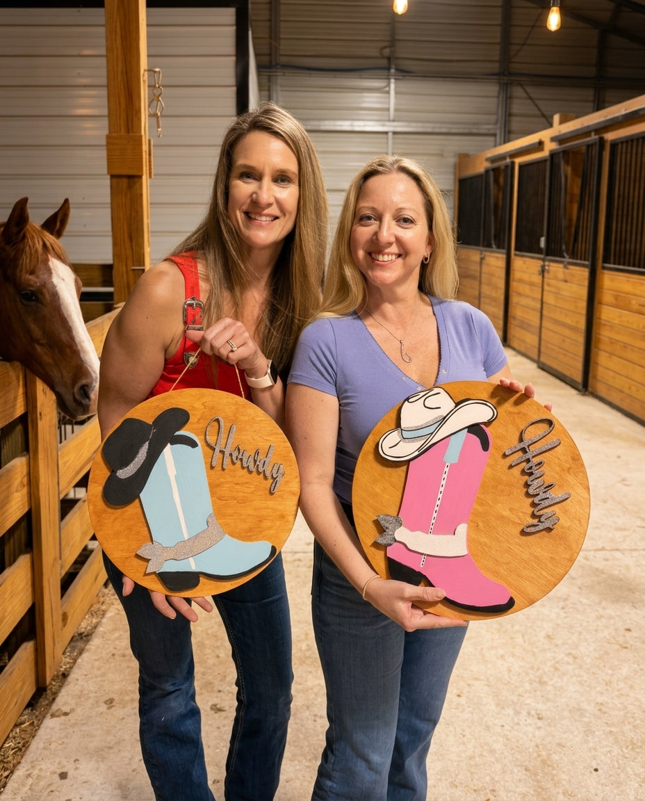 Guests at a ladies night event at Rodeo Stables in Ormond Beach, Florida holding western-inspired painted signs inside the horse barn
