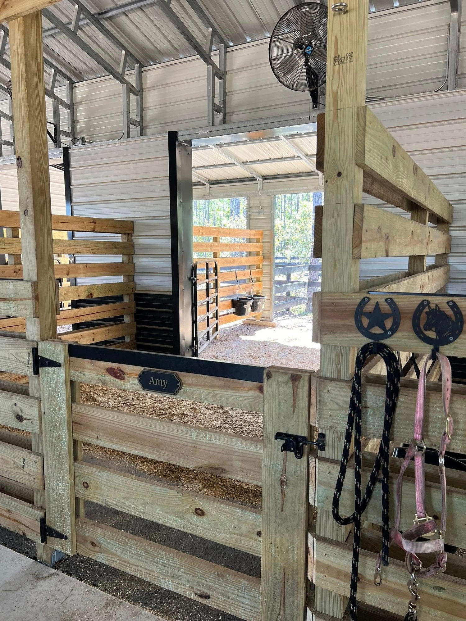 Private horse stall with wooden gates and tack hooks inside Rodeo Stables in Ormond Beach, Florida