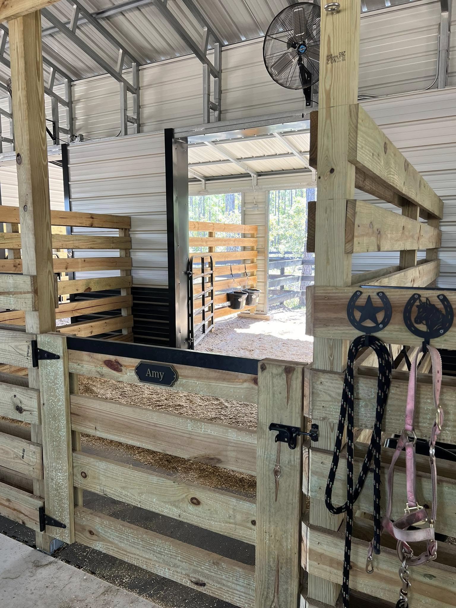 Private horse stall with wooden gates and tack hooks inside Rodeo Stables in Ormond Beach, Florida